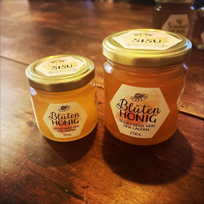 Zwei Gläser Pure-Sisu-Blütenhonig auf einem Holztisch