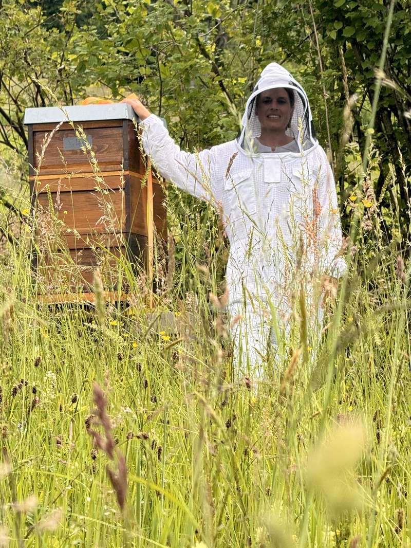 Mara Wieser im Imkeranzug bei ihren Bienenstöcken auf der Wiese